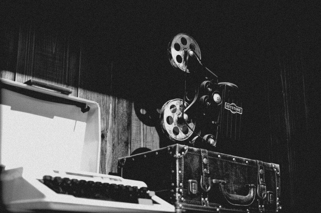 Monochrome image of a vintage typewriter and retro film projector evoking historical nostalgia.